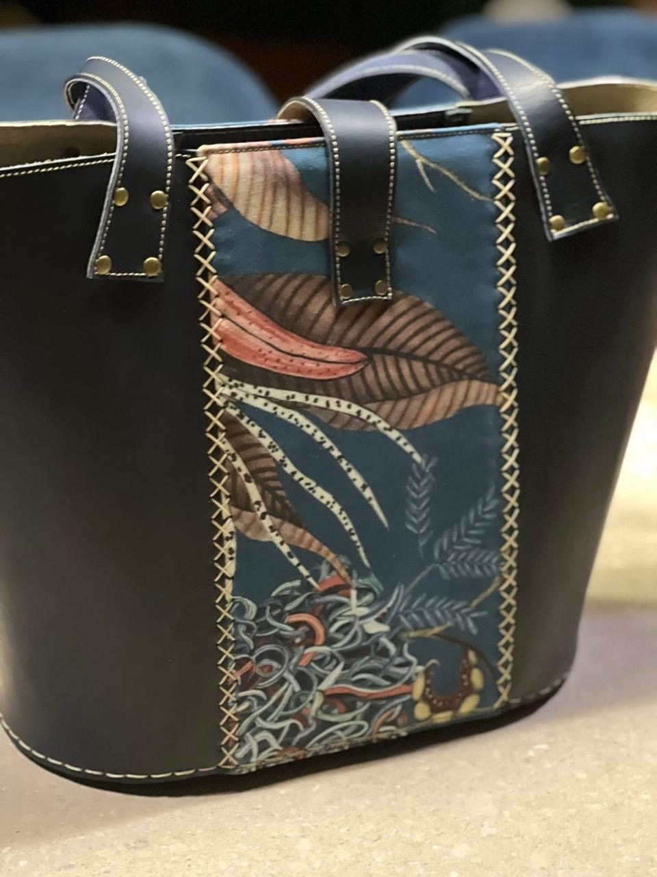 Close-up of a leaf tapestry panel on a navy tote